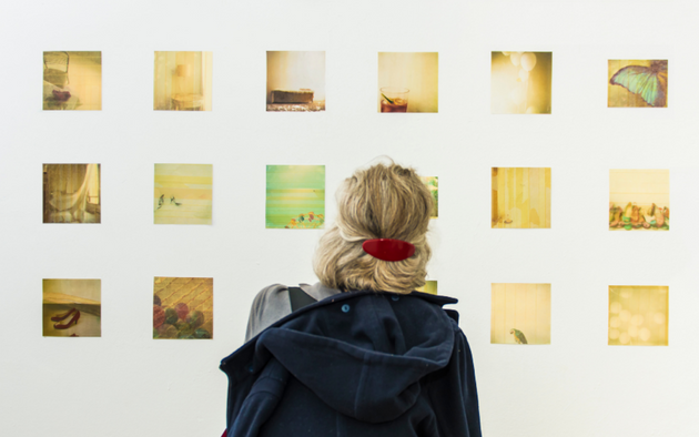 A woman looks at a wall of artwork.