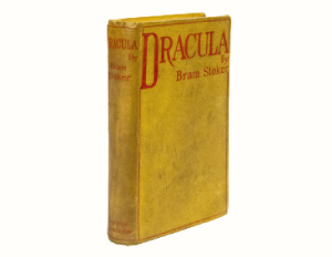 Yellow cover of worn book with red lettering reading Dracula Bram Stoker,